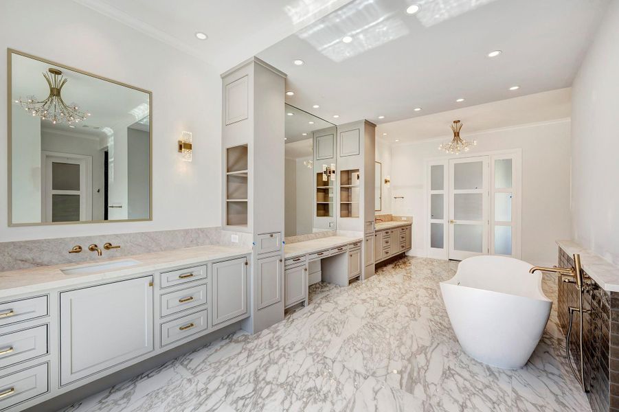 Expansive primary bathroom with a luxurious soaking tub, dual vanities with separate sinks, dedicated vanity seating, and abundant countertop and storage space.