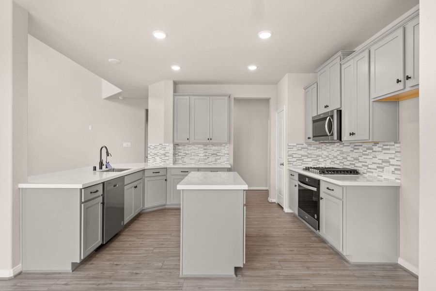 The kitchen features cool stained cabinetry, quartz countertops and a modern subway tile backsplash.