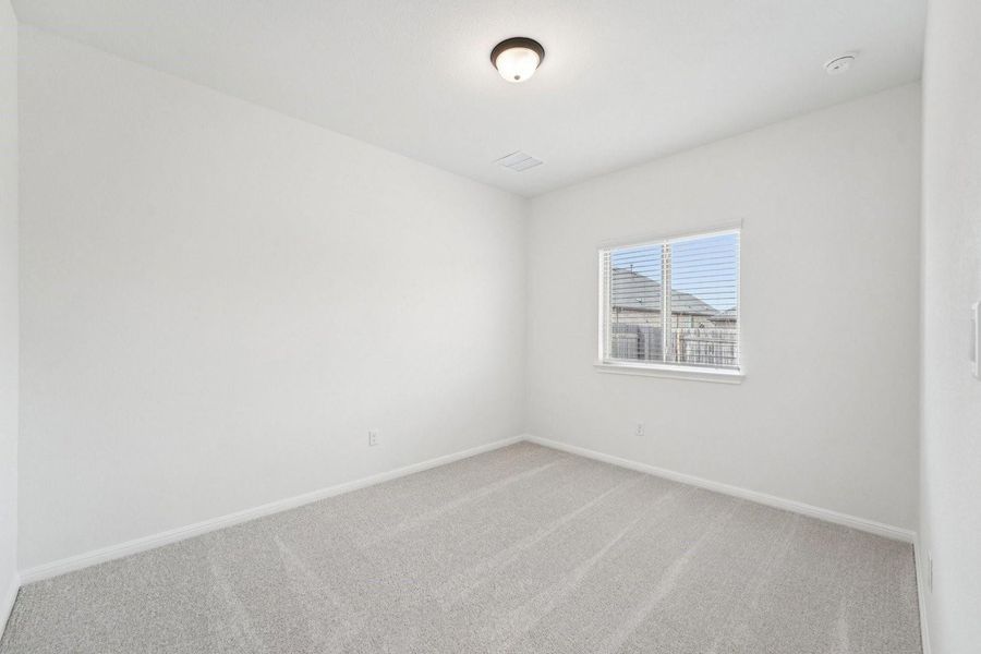 A well-lit bedroom features plush carpeting and a bright window with horizontal blinds. A well-lit bedroom features plush carpeting and a bright window with horizontal blinds.