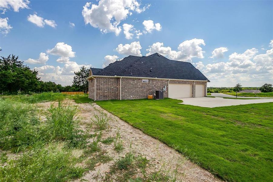 View of side of property featuring a garage and a lawn