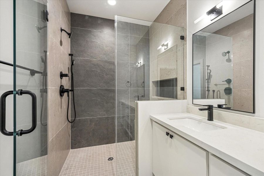 Spa-inspired primary bath featuring double sinks, floating cabinetry, and a large glass-enclosed shower with both a standard and handheld shower head.