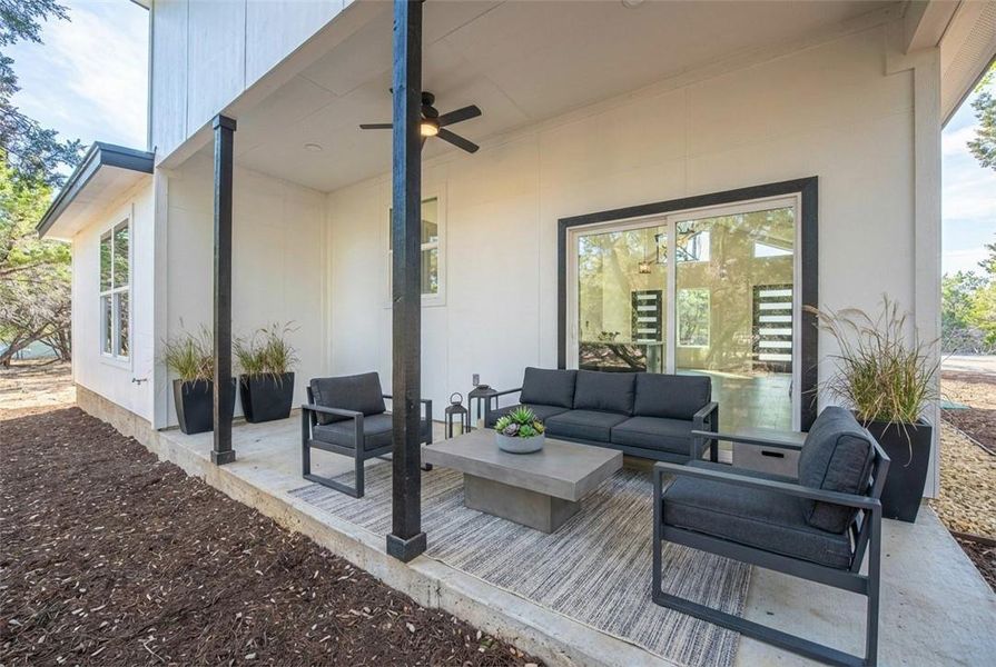 Sliding glass doors open onto a concrete patio supported by dark structural posts. Sliding glass doors open onto a concrete patio supported by dark structural posts.