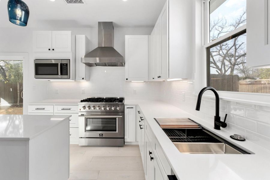 Kitchen featuring stainless steel appliances, white cabinetry, decorative backsplash, and recessed lighting