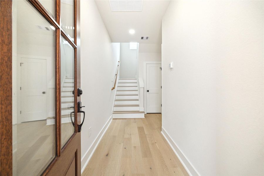 Step into a bright and welcoming entrance, featuring elegant wood flooring and a modern, open staircase leading to your new home. Step into a bright and welcoming entrance, featuring elegant wood flooring and a modern, open staircase leading to your new home.