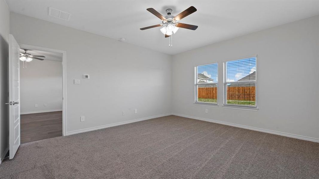 Carpeted empty room with ceiling fan and baseboards Carpeted empty room with ceiling fan and baseboards