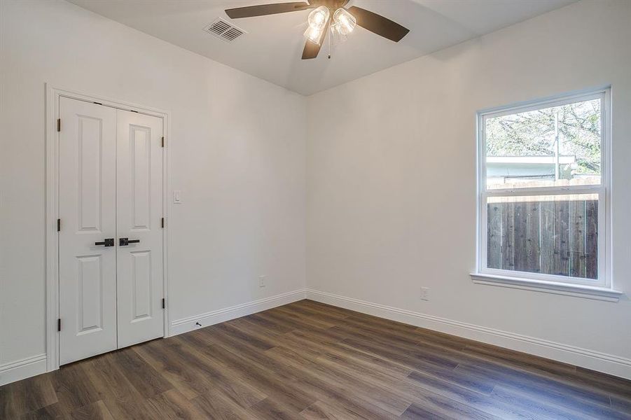 Unfurnished room with dark wood-type flooring and ceiling fan