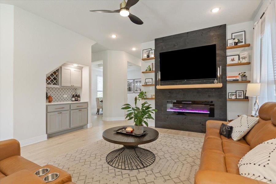 Living room with a ceiling fan, light wood finished floors, and a fireplace