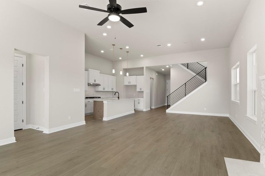 Unfurnished living room featuring stairway, recessed lighting, ceiling fan, and light wood-type flooring Unfurnished living room featuring stairway, recessed lighting, ceiling fan, and light wood-type flooring