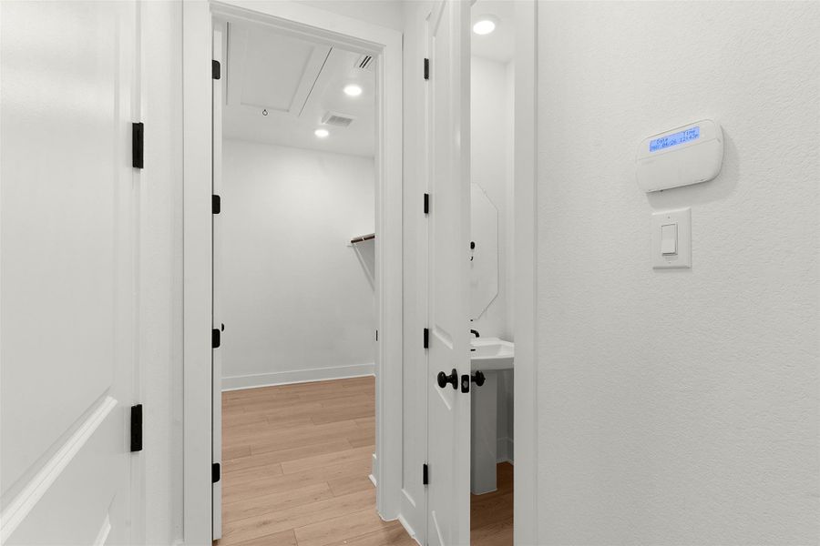 Hallway featuring light wood-finish flooring, recessed lighting, and white baseboards Hallway featuring light wood-finish flooring, recessed lighting, and white baseboards