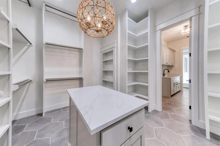 Walk in closet featuring light tile patterned flooring, a chandelier, and sink