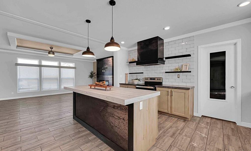 Kitchen with light brown cabinets, tasteful backsplash, wood tiled floors, stainless steel electric range, and wall chimney range hood Kitchen with light brown cabinets, tasteful backsplash, wood tiled floors, stainless steel electric range, and wall chimney range hood