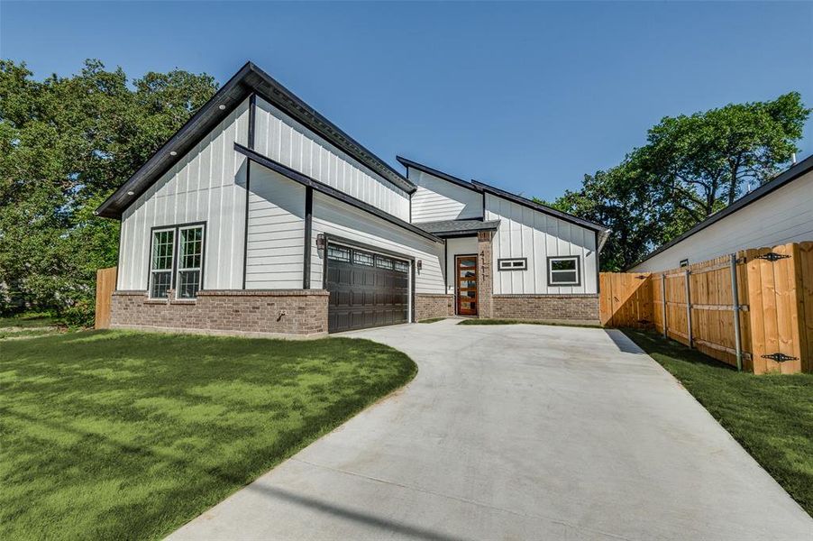 View of front of house with board and batten siding, brick siding, concrete driveway, and a garage View of front of house with board and batten siding, brick siding, concrete driveway, and a garage