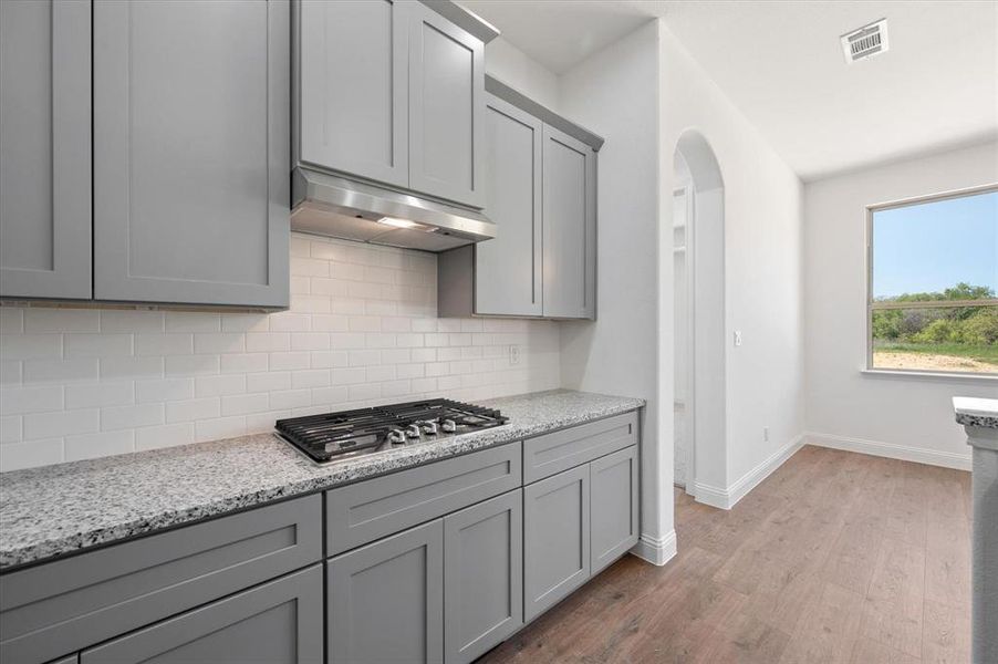 Kitchen featuring gray cabinets, stainless steel gas stovetop, and light hardwood / wood-style flooring