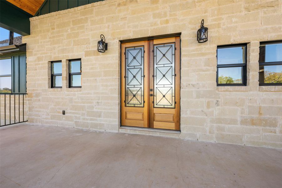 Doorway to property featuring stone siding, a patio, and board and batten siding