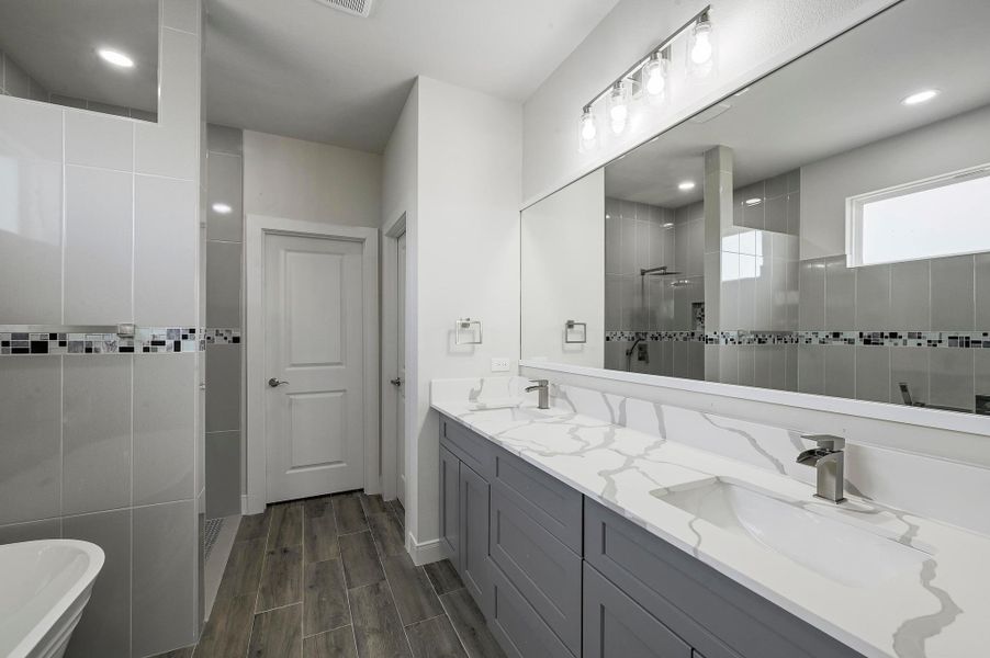 Bathroom featuring a walk in shower, double vanity, a soaking tub, and wood finish floors Bathroom featuring a walk in shower, double vanity, a soaking tub, and wood finish floors