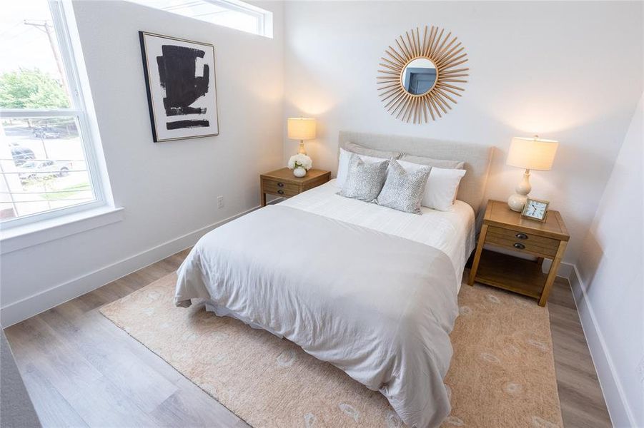 Bedroom with light hardwood / wood-style flooring and multiple windows