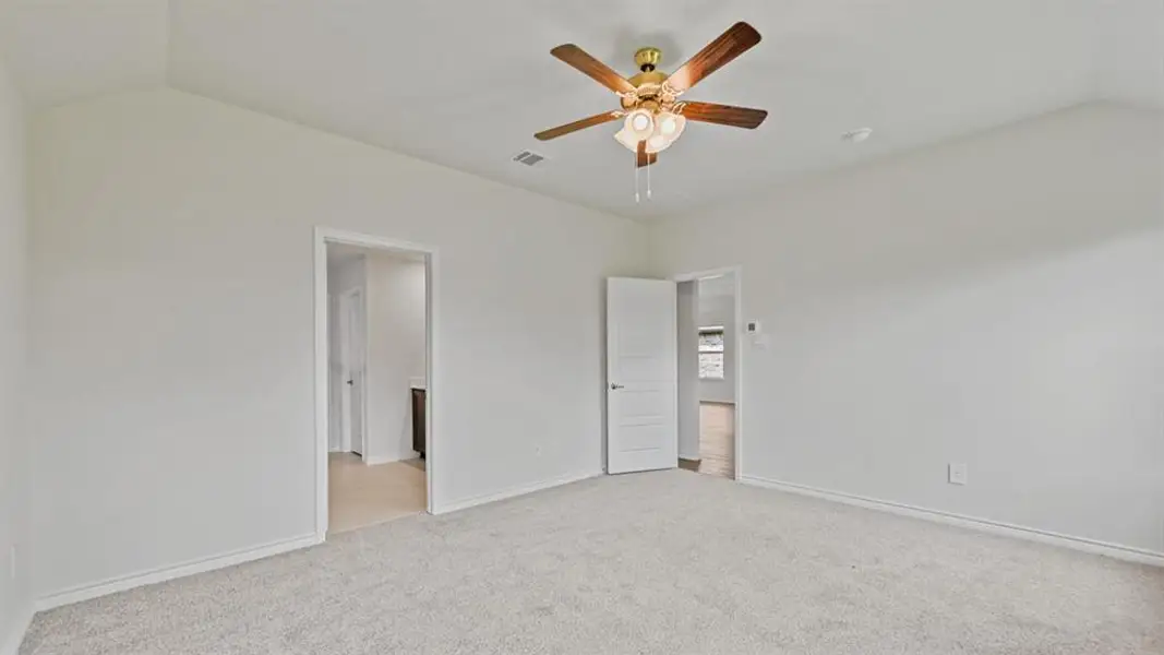 Spacious room featuring vaulted ceilings, light-toned carpeting, and a ceiling fan with integrated lighting Spacious room featuring vaulted ceilings, light-toned carpeting, and a ceiling fan with integrated lighting