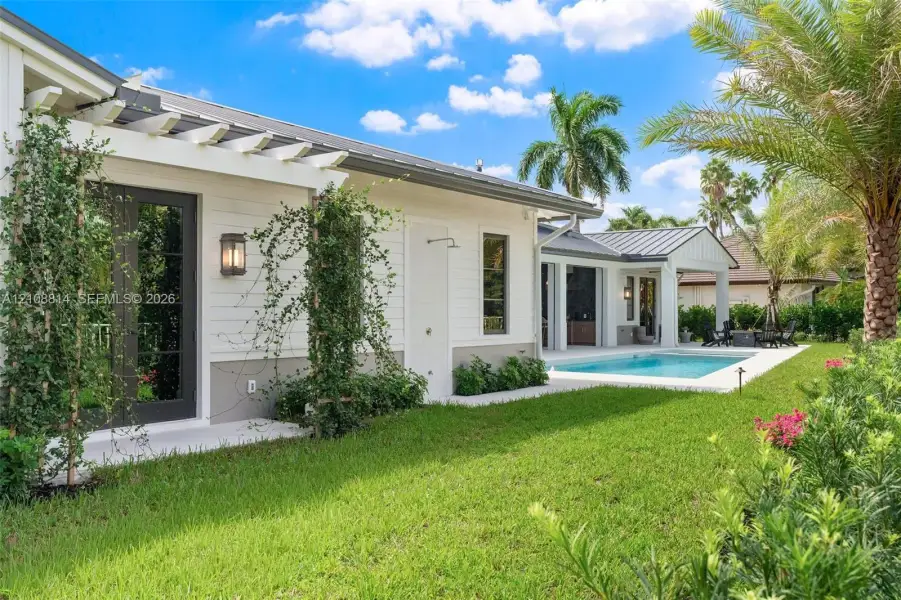 Exterior featuring white lap siding, a metal roof, pergola-covered patio, outdoor shower, and swimming pool Exterior featuring white lap siding, a metal roof, pergola-covered patio, outdoor shower, and swimming pool