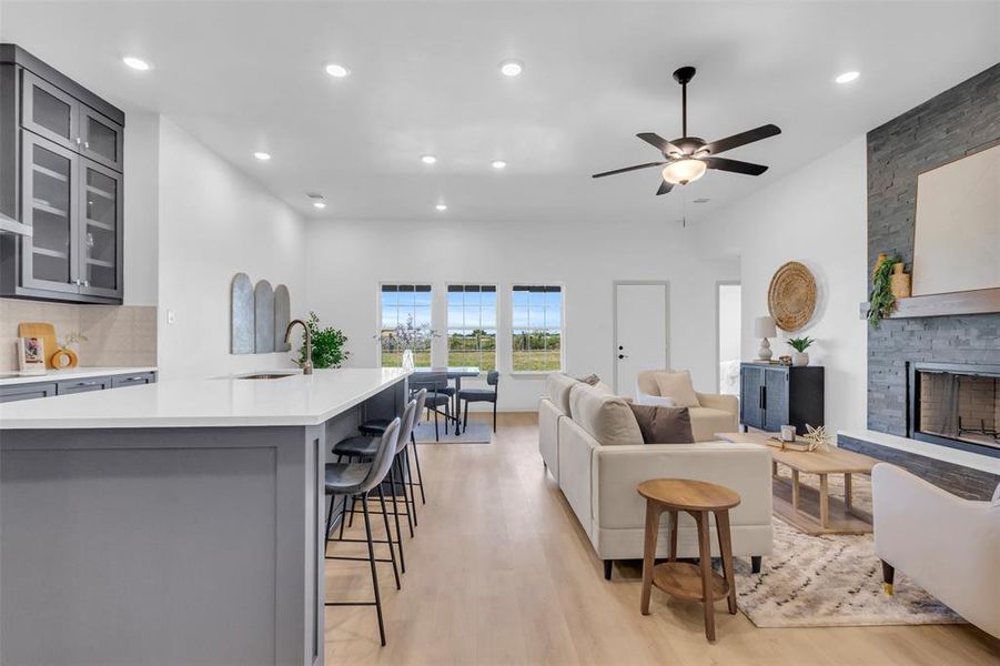 Living room with light wood-style floors, a fireplace, recessed lighting, and a ceiling fan Living room with light wood-style floors, a fireplace, recessed lighting, and a ceiling fan