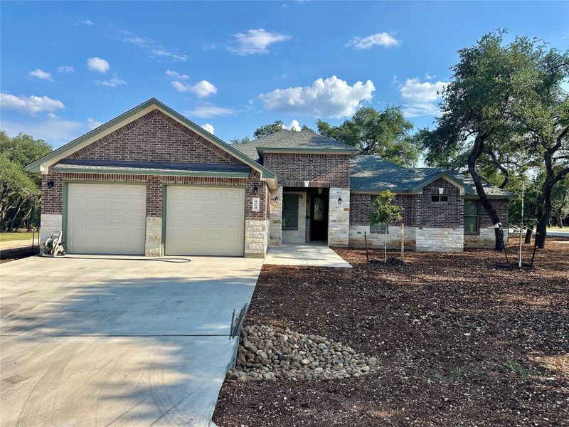Ranch-style house with concrete driveway, an attached garage, stone siding, and brick siding