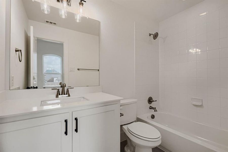 Bathroom featuring a white vanity with an integrated sink, brushed nickel faucet, and a large frameless mirror Bathroom featuring a white vanity with an integrated sink, brushed nickel faucet, and a large frameless mirror
