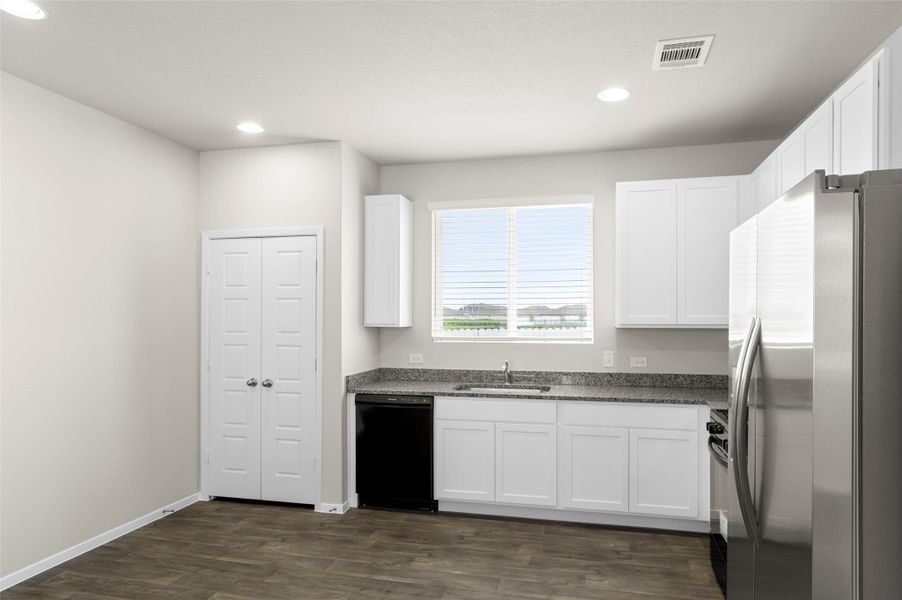 Kitchen featuring freestanding refrigerator, dishwasher, white cabinets, dark wood-type flooring, and recessed lighting