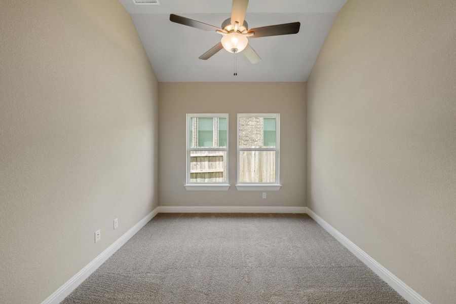 Carpeted empty room with vaulted ceiling, a ceiling fan, and a textured wall