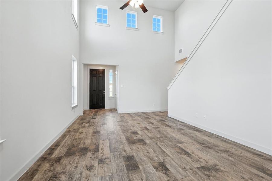 Foyer entrance with wood finished floors, a high ceiling, and a ceiling fan Foyer entrance with wood finished floors, a high ceiling, and a ceiling fan