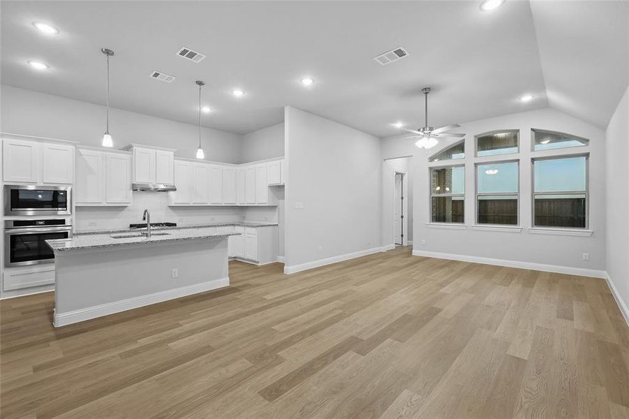 Kitchen with appliances with stainless steel finishes, a ceiling fan, white cabinets, decorative backsplash, and open floor plan Kitchen with appliances with stainless steel finishes, a ceiling fan, white cabinets, decorative backsplash, and open floor plan