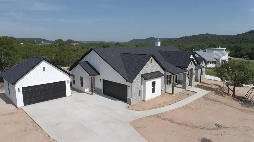 Modern farmhouse featuring a shingled roof, board and batten siding, concrete driveway, and a garage Modern farmhouse featuring a shingled roof, board and batten siding, concrete driveway, and a garage