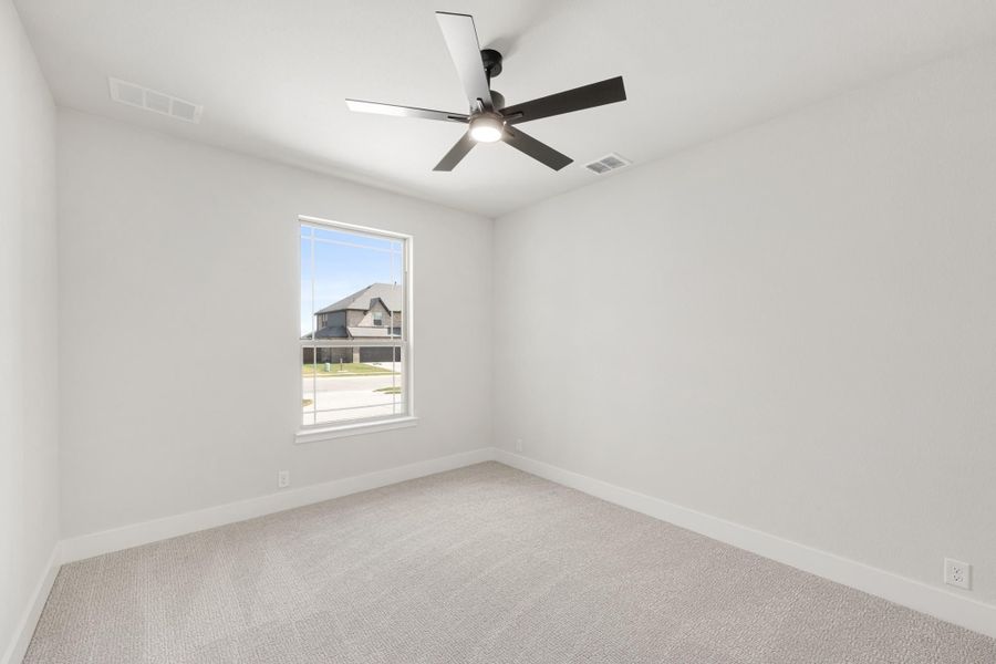 Empty bedroom with light carpet, white walls, ceiling fan, and single window with neighborhood view