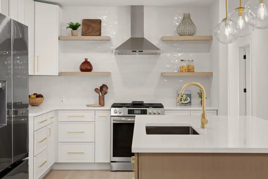 Kitchen with open shelves, stainless steel appliances, light stone counters, a kitchen island, and dual tone cabinets