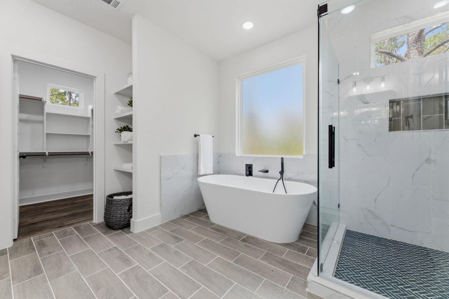 Indulge in a luxurious primary bath, featuring a sleek soaking tub and an elegant walk-in shower.