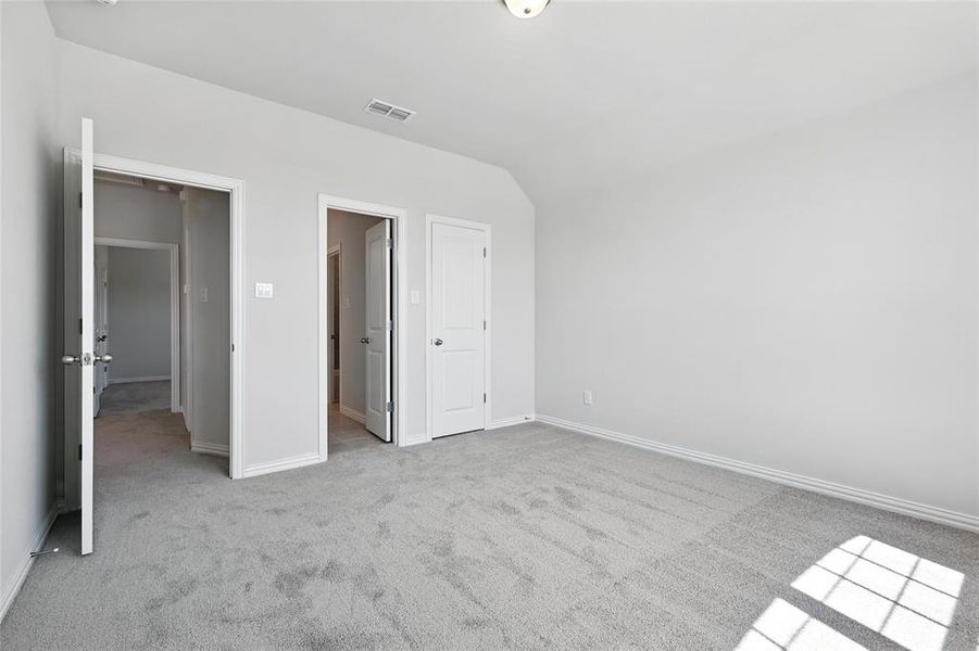 Unfurnished bedroom with light carpet and lofted ceiling