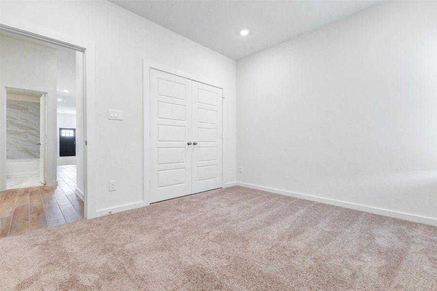 Additional secondary bedroom with plush carpet, neutral walls, recessed lighting, and a double-door closet. The room offers a clean, move-in-ready feel and can easily serve as a bedroom, office, playroom, or guest space.