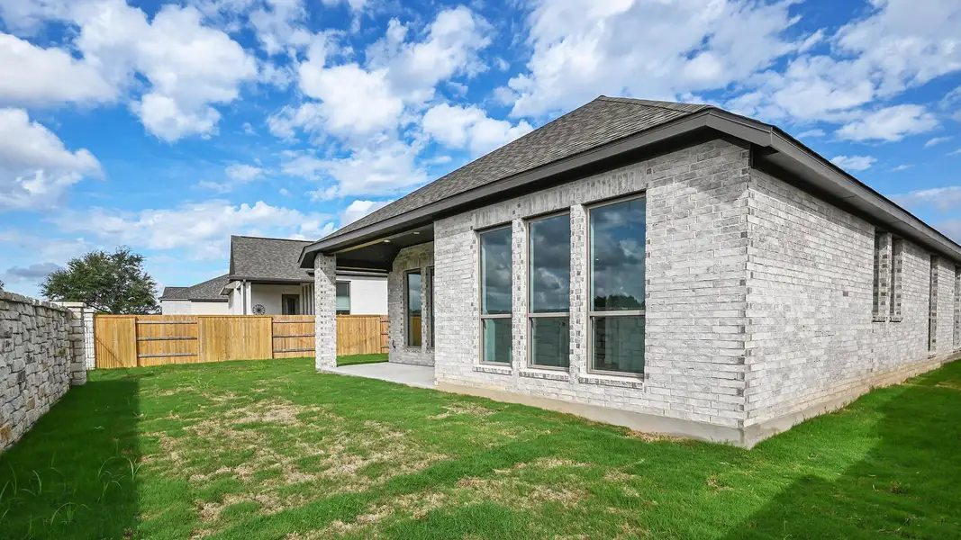 Back of property with brick siding, a patio, a fenced backyard, and a shingled roof