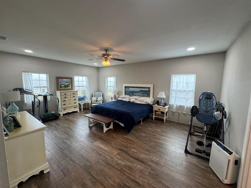 Bedroom featuring multiple windows, dark wood-style floors, a ceiling fan, and recessed lighting Bedroom featuring multiple windows, dark wood-style floors, a ceiling fan, and recessed lighting