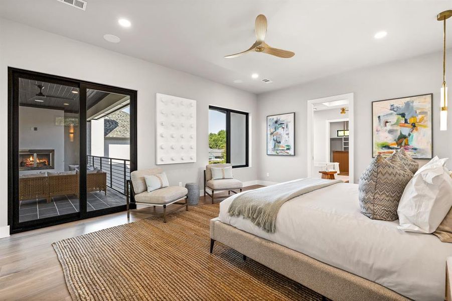 Bedroom featuring recessed lighting, multiple windows, a warm lit fireplace, access to outside, and wood finished floors Bedroom featuring recessed lighting, multiple windows, a warm lit fireplace, access to outside, and wood finished floors
