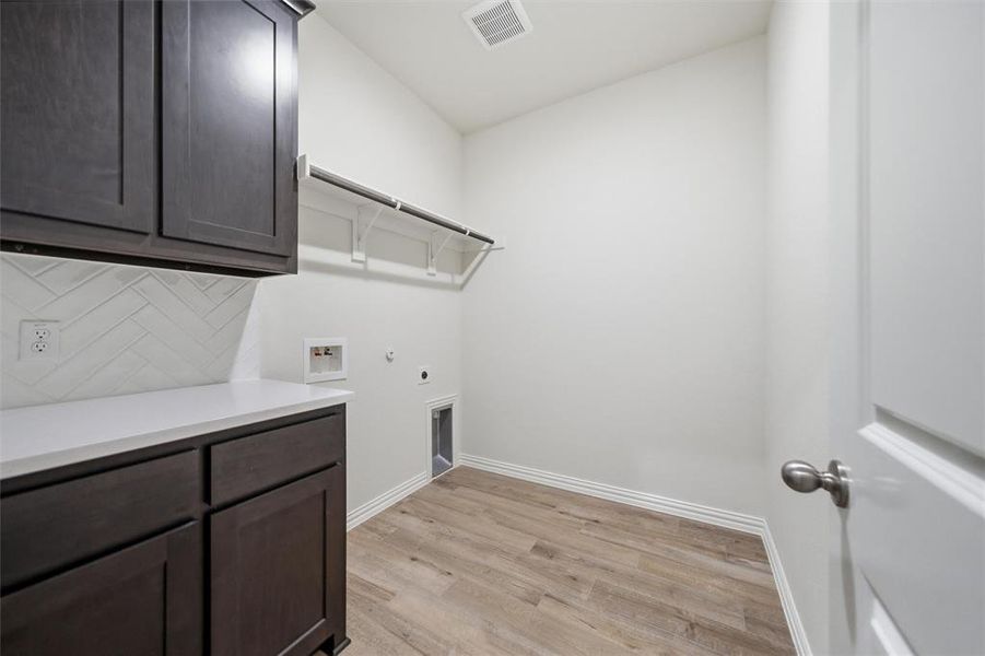 Laundry room with gas dryer hookup, light wood-type flooring, washer hookup, hookup for an electric dryer, and cabinet space