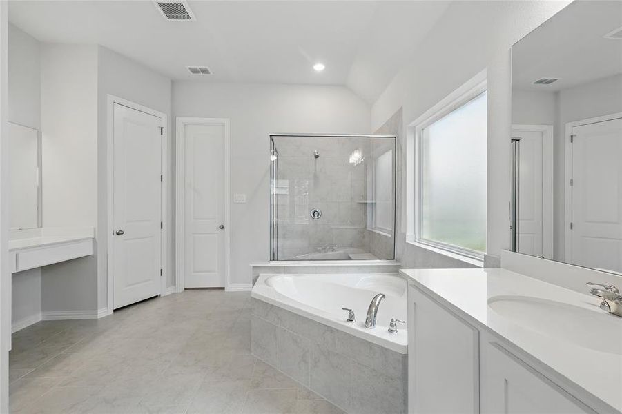 Bathroom featuring a garden tub, vanity, and a stall shower Bathroom featuring a garden tub, vanity, and a stall shower
