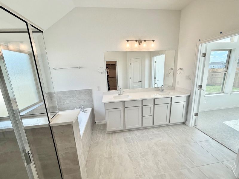 Full bathroom featuring a stall shower, double vanity, a garden tub, a closet, and lofted ceiling
