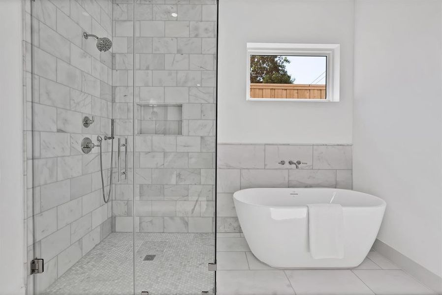 Freestanding soaking tub alongside a walk-in shower with glass enclosure, subway tile surround, and hexagonal tile flooring