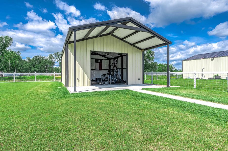Another view of the versatile barn-style building highlights the spacious setup and flexibility this additional structure offers. Currently utilized as a private gym, the space can easily adapt to a variety of uses including storage, hobbies, recreation, or workshop space.