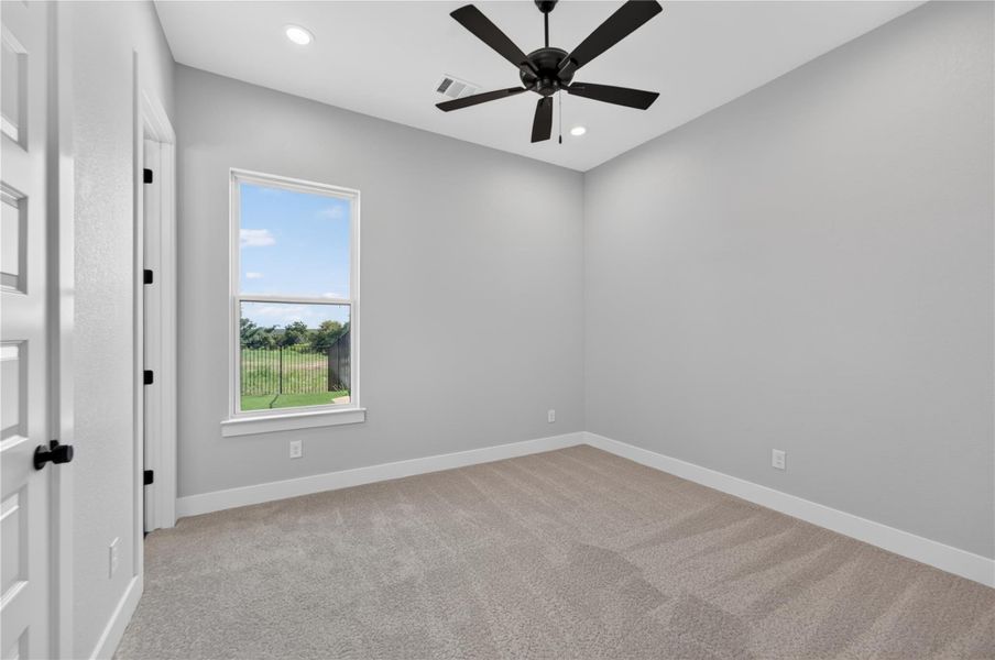 High ceilings and neutral carpet define this versatile space, highlighted by a large window.