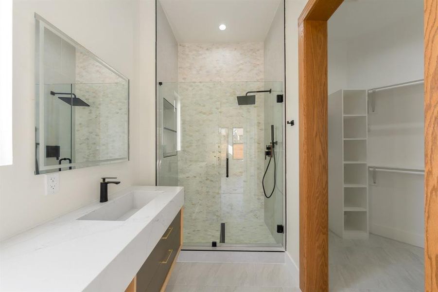 Bathroom featuring a stall shower, vanity, and a spacious closet Bathroom featuring a stall shower, vanity, and a spacious closet