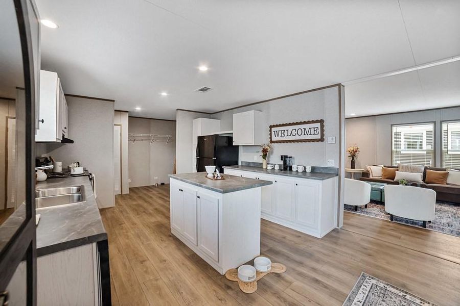 Kitchen with white cabinetry, refrigerator, and a kitchen island. Kitchen with white cabinetry, refrigerator, and a kitchen island.