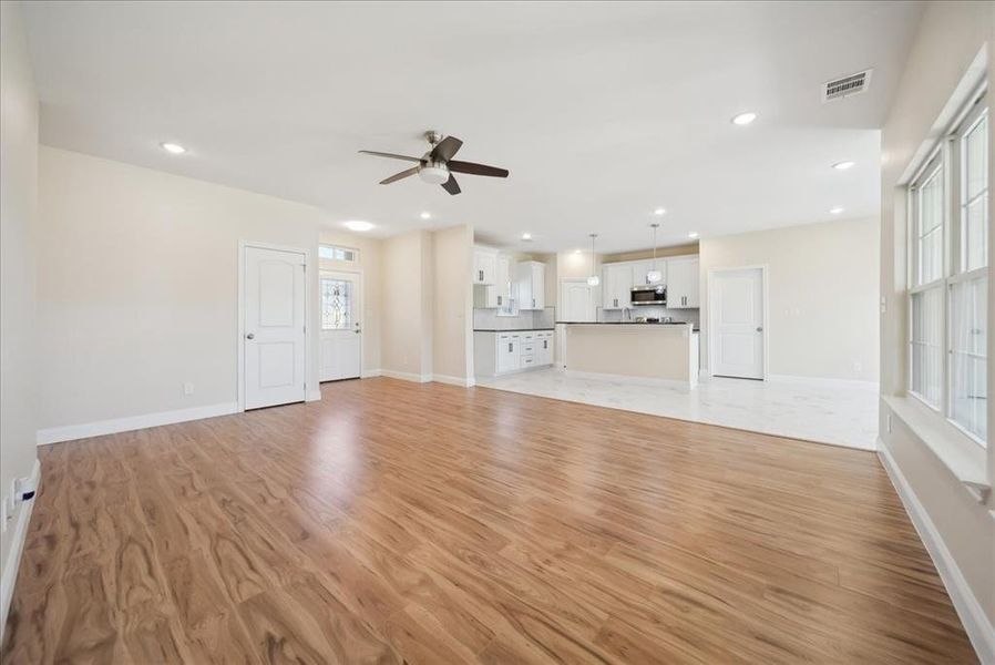 Unfurnished living room with ceiling fan and light hardwood / wood-style flooring