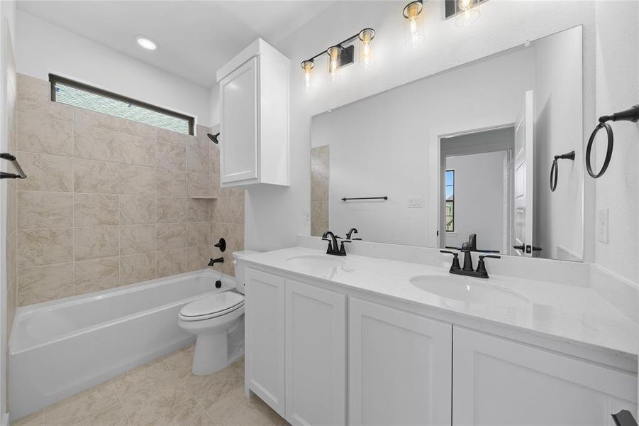 Bathroom featuring a dual vanity with white cabinetry and countertops, a large frameless mirror, and matte black fixtures