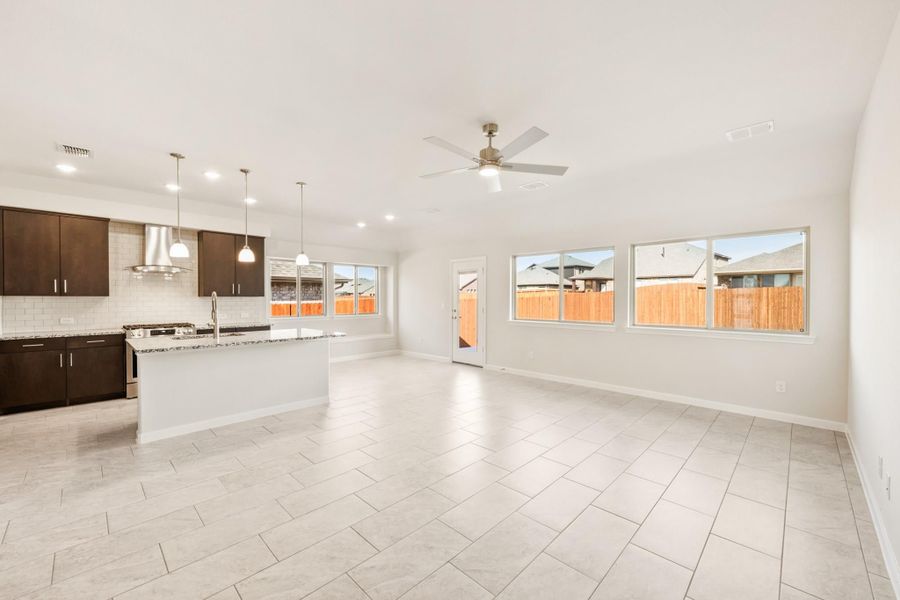 Open-concept living area and kitchen with dark cabinets, center island, tile floors, and ceiling fan Open-concept living area and kitchen with dark cabinets, center island, tile floors, and ceiling fan