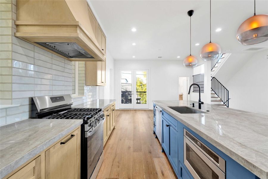 The kitchen features custom-built cabinets, Taj Mahal countertops, ample storage, a walk-in pantry, and built-in microwave drawers.